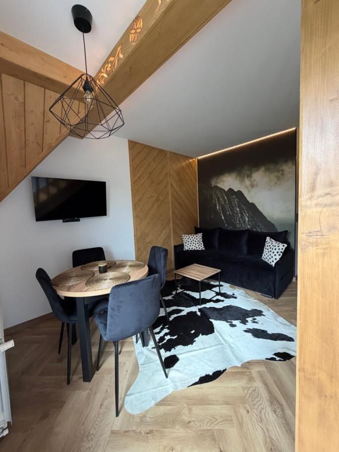 Stół i granatowa sofa w drewnianym wnętrzu