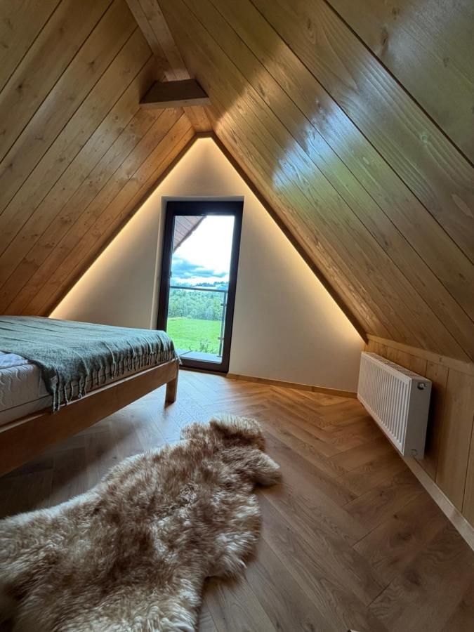 Sypialnia pod drewnianymi skosami z oknem na krajobraz